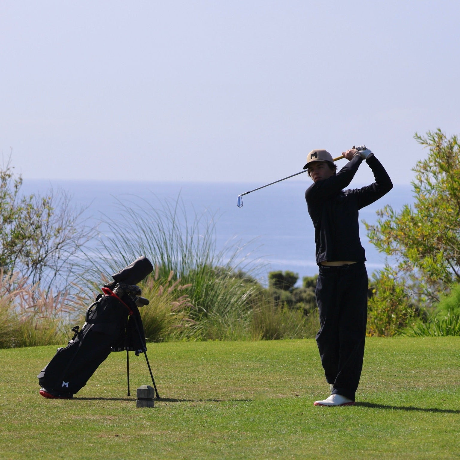 Golfer in action on a golf course with ocean view