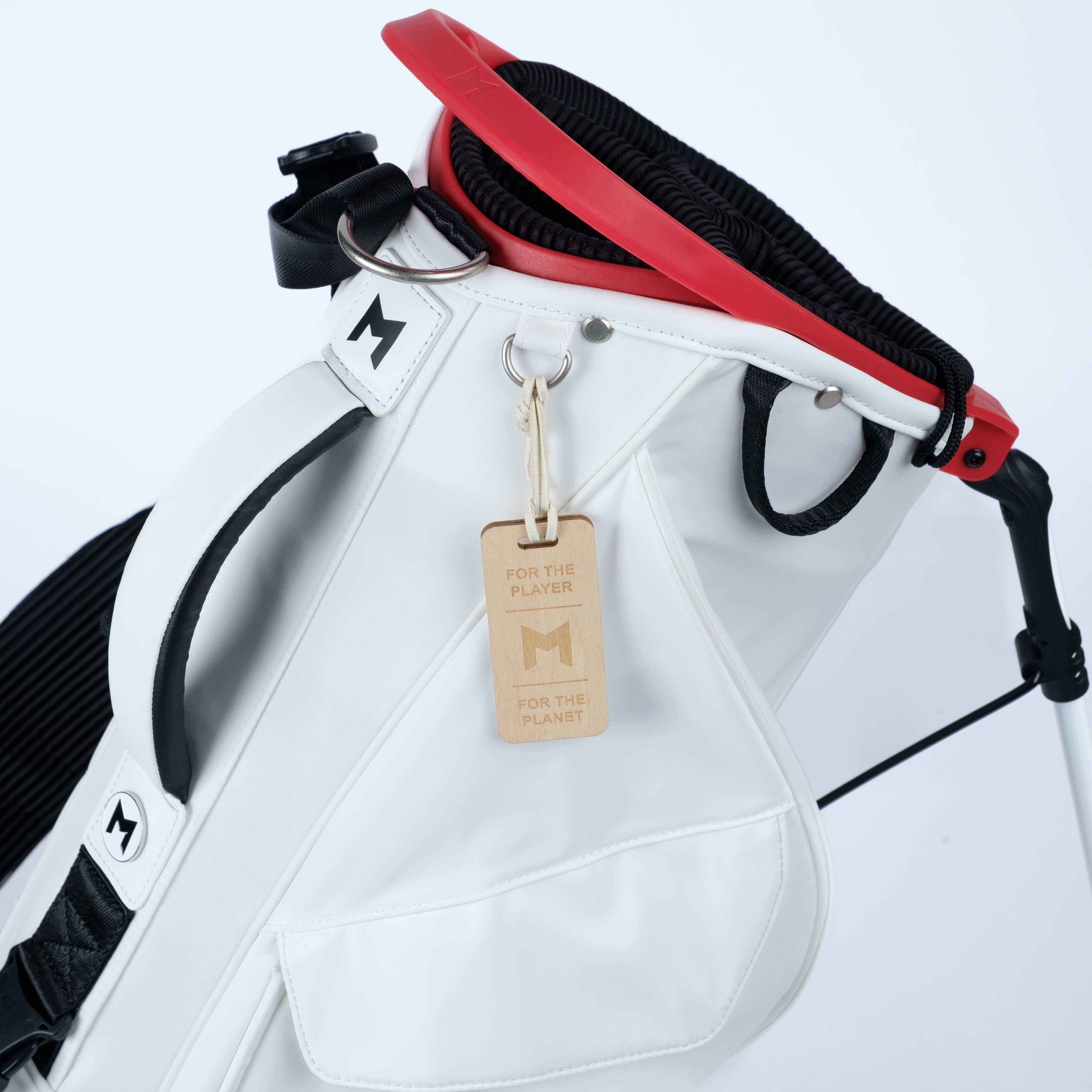White golf bag with red and black strap on a light gray background