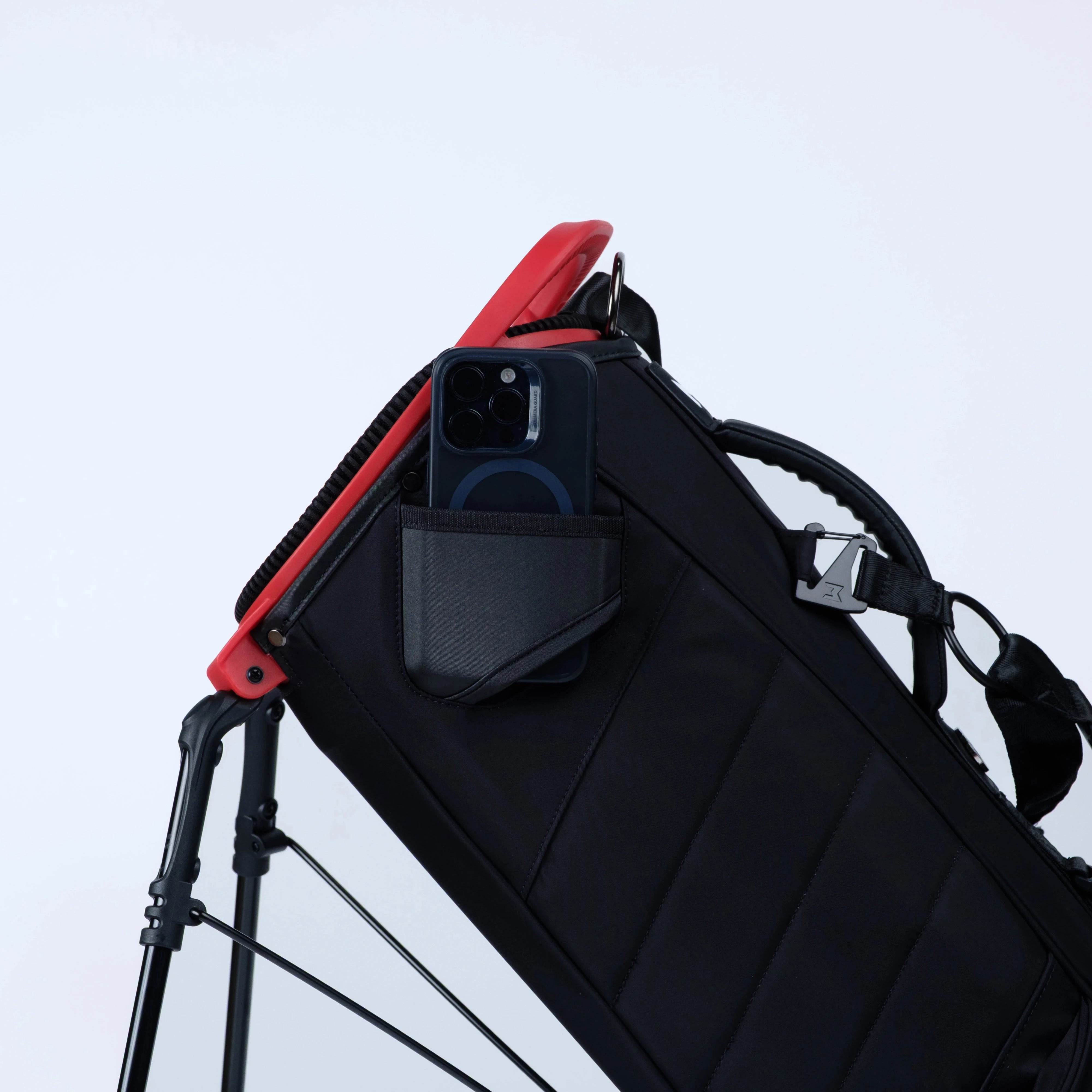 Black and red backpack with a camera attached on a light gray background