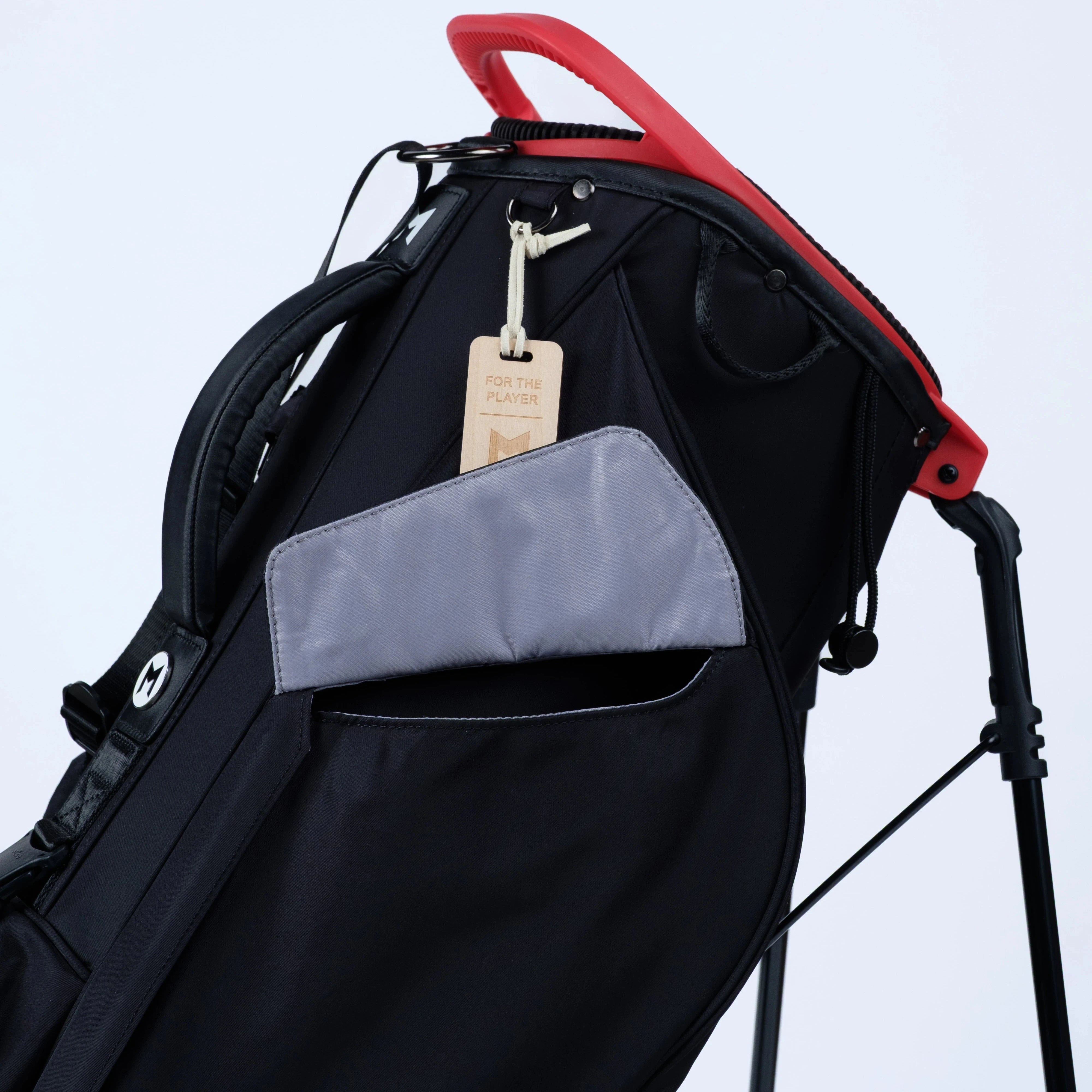 Black golf bag with a gray lining and red accents on a light blue background