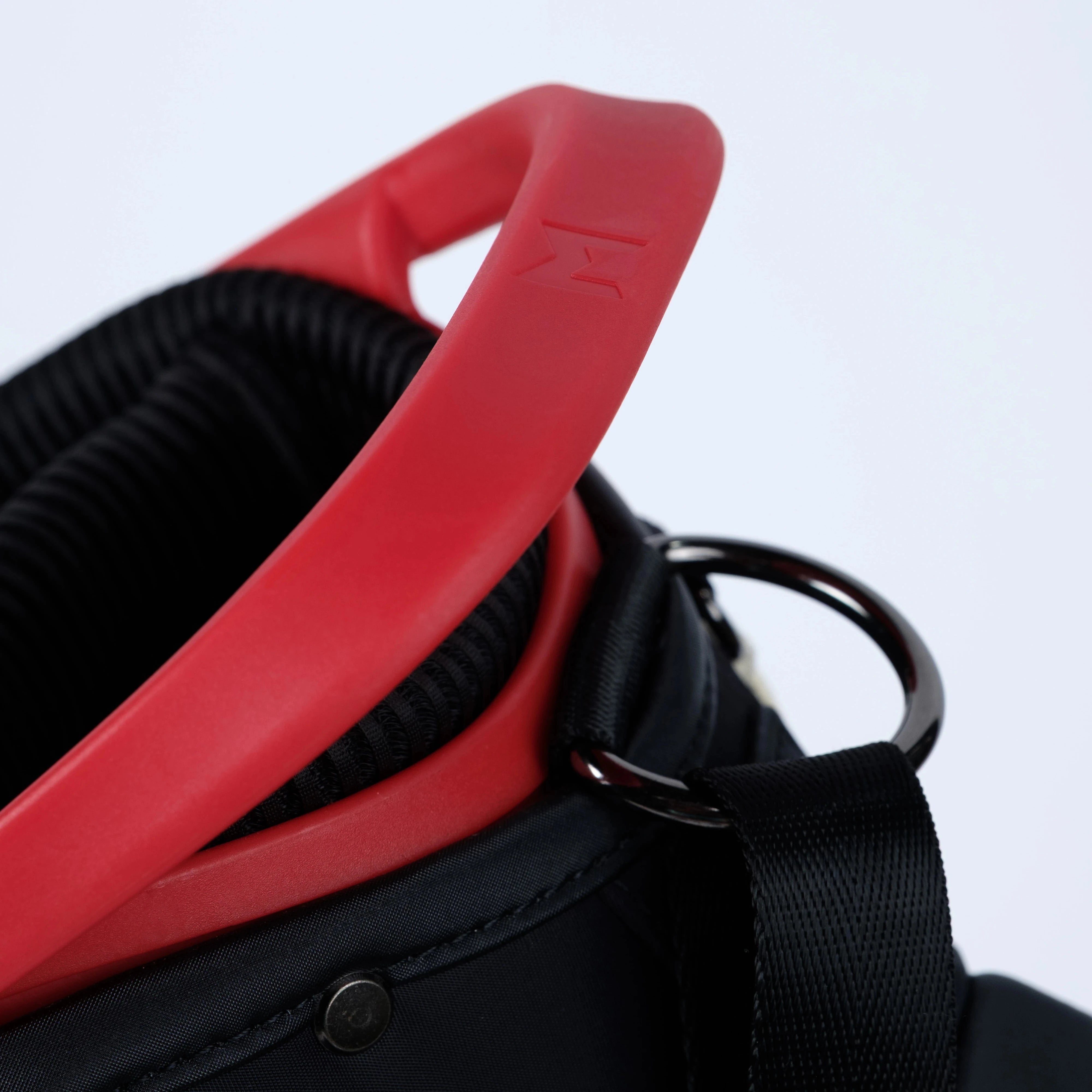 Close-up of a black bag with a red handle on a light gray background