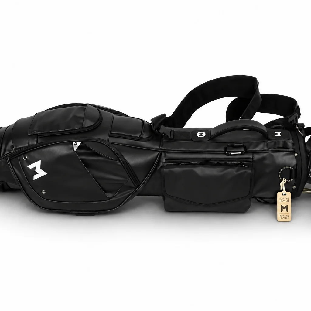 A black golf bag with multiple compartments, shoulder strap, and attached golf clubs, shown on a clean white background. The bag features a white stylized logo on the side and a small wooden hangtag.