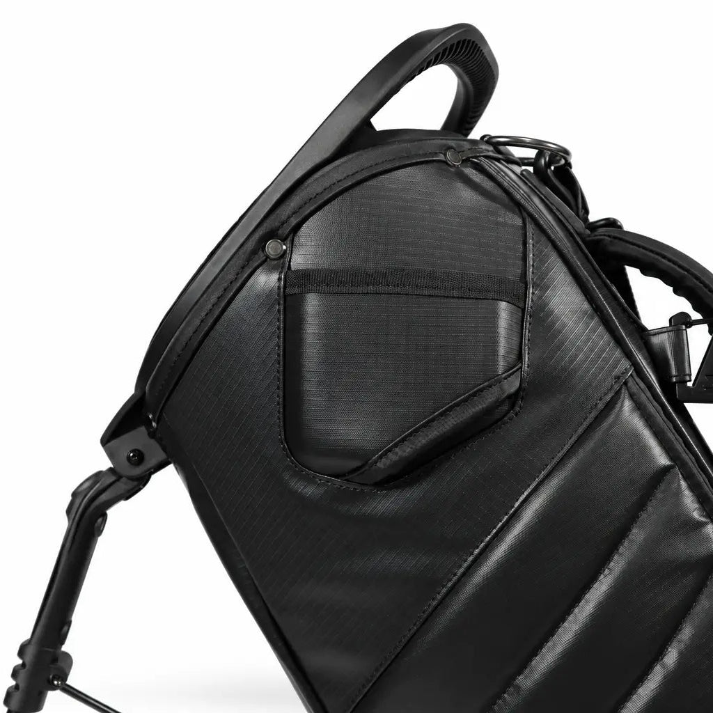 Close-up of a black golf bag showing the top handle, filming pocket, and shoulder strap details against a white background.