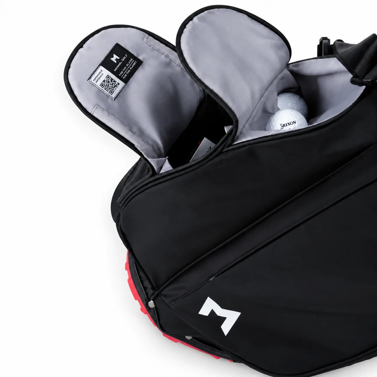 A black golf bag with a white stylized 'M' logo on the front, shown open to reveal a gray interior containing golf balls in magnetic pockets. The bag is photographed on a clean white background.