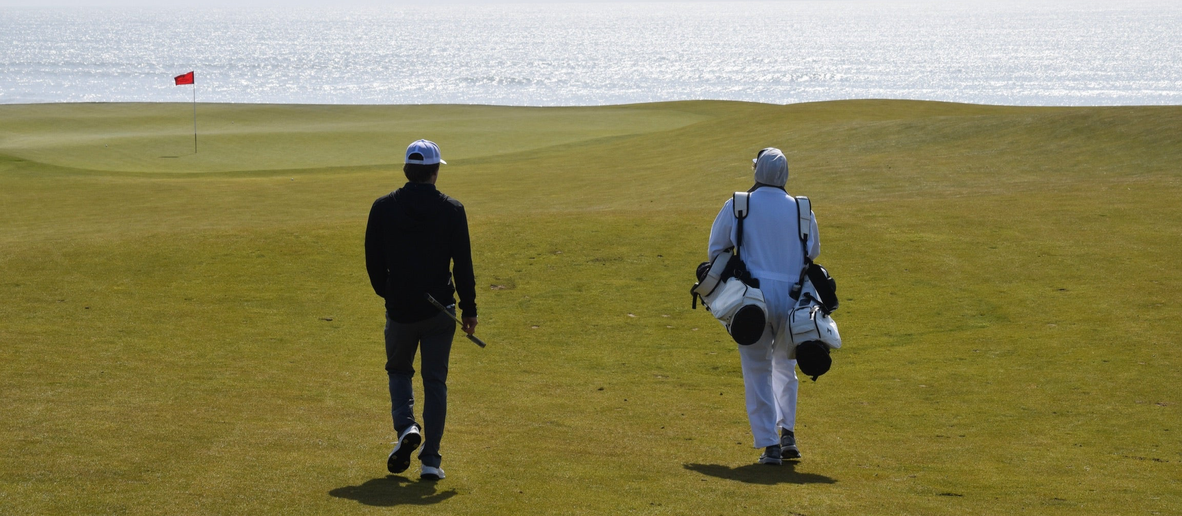 MNML GOLF team member, Campbell and caddy, walking down the fairway at Chamber's Bay golf course.