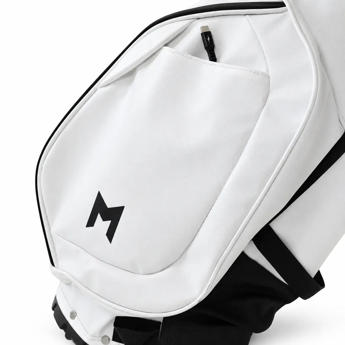 Close-up of a white golf bag with black trim, a black logo on the front pocket, and black straps against a white background.