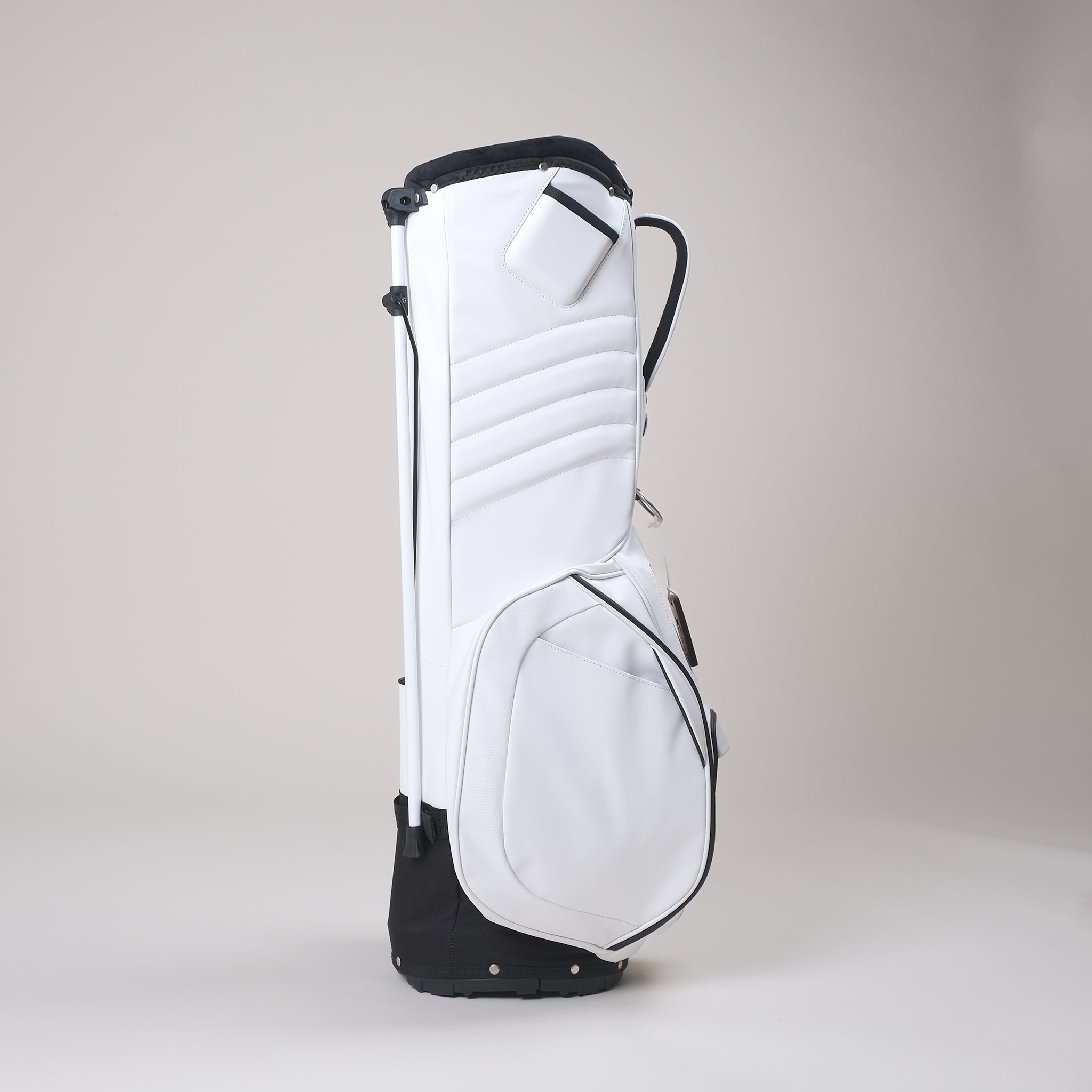 Side view of white MNML GOLF bag displaying phone pocket for filming, extra storage magnetic pockets, standing golf bag and handle.