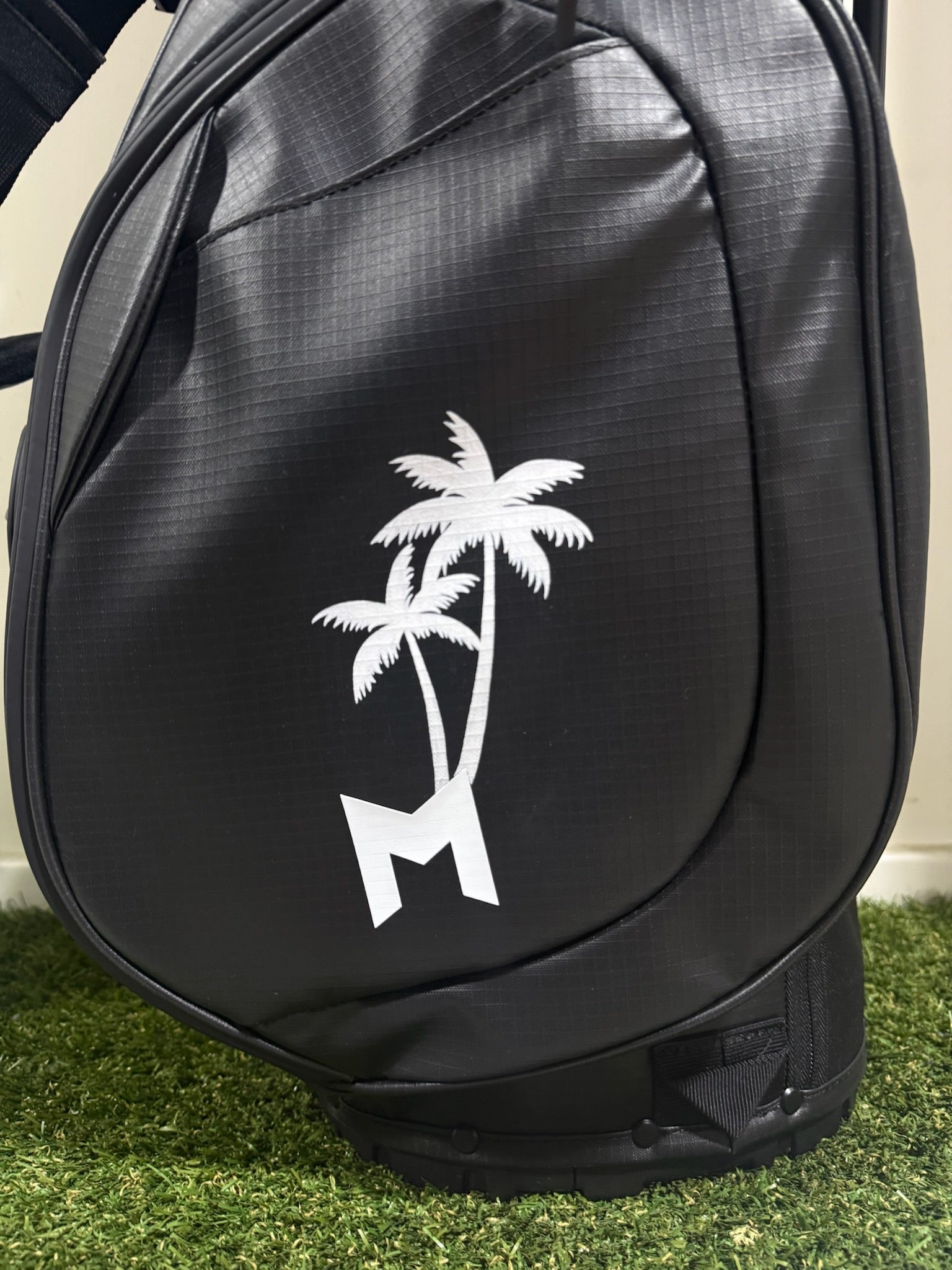 Black golf bag with white palm tree design hand painted on grass