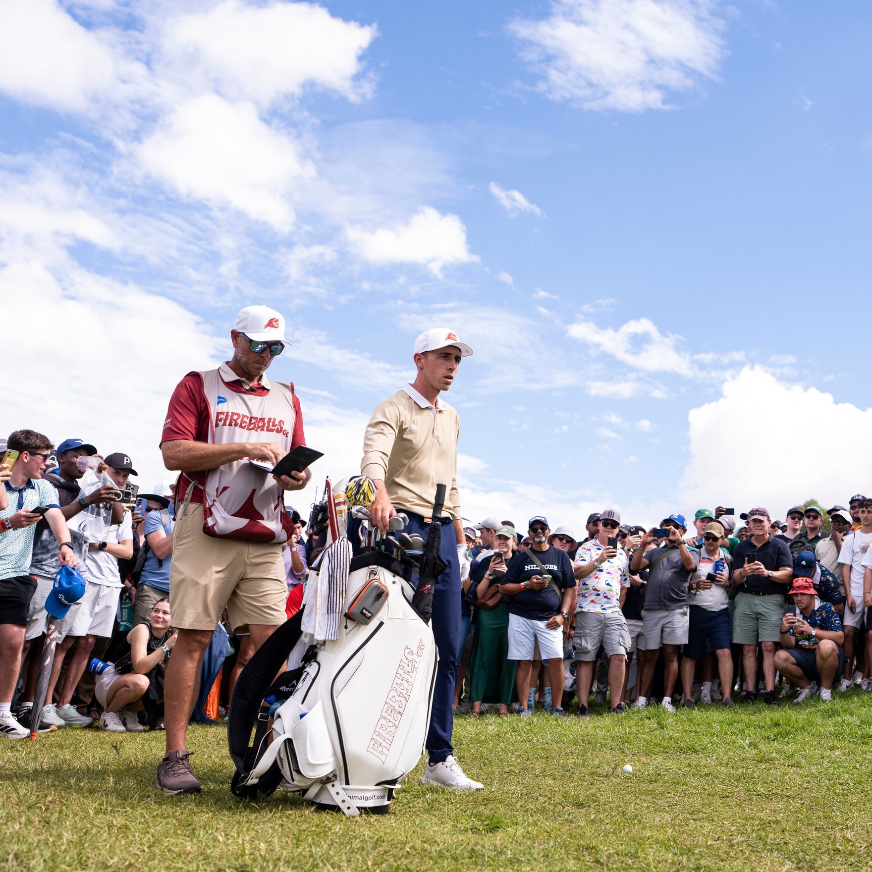 Golfers on a green with a crowd and blue sky