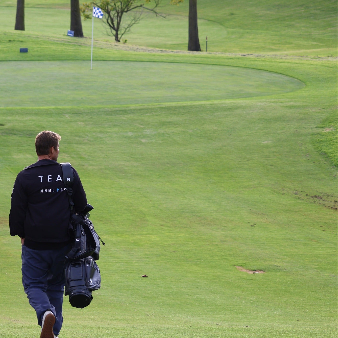 Two golfers walking on a golf course with golf bags.