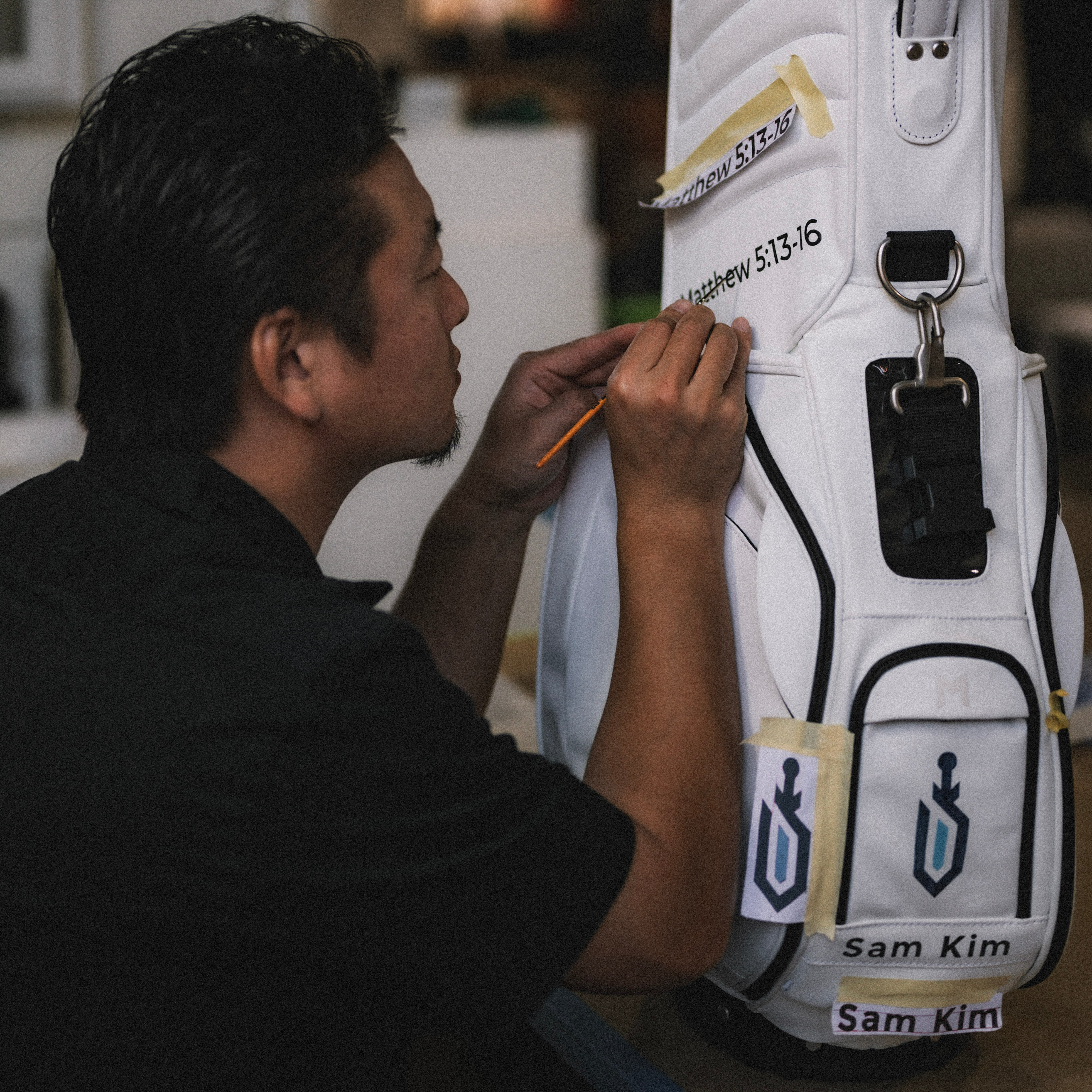 MNML GOLF's lead artist, Hitoshi, hand-painting a graphic on a white MR1 customizable golf bag for a customer.