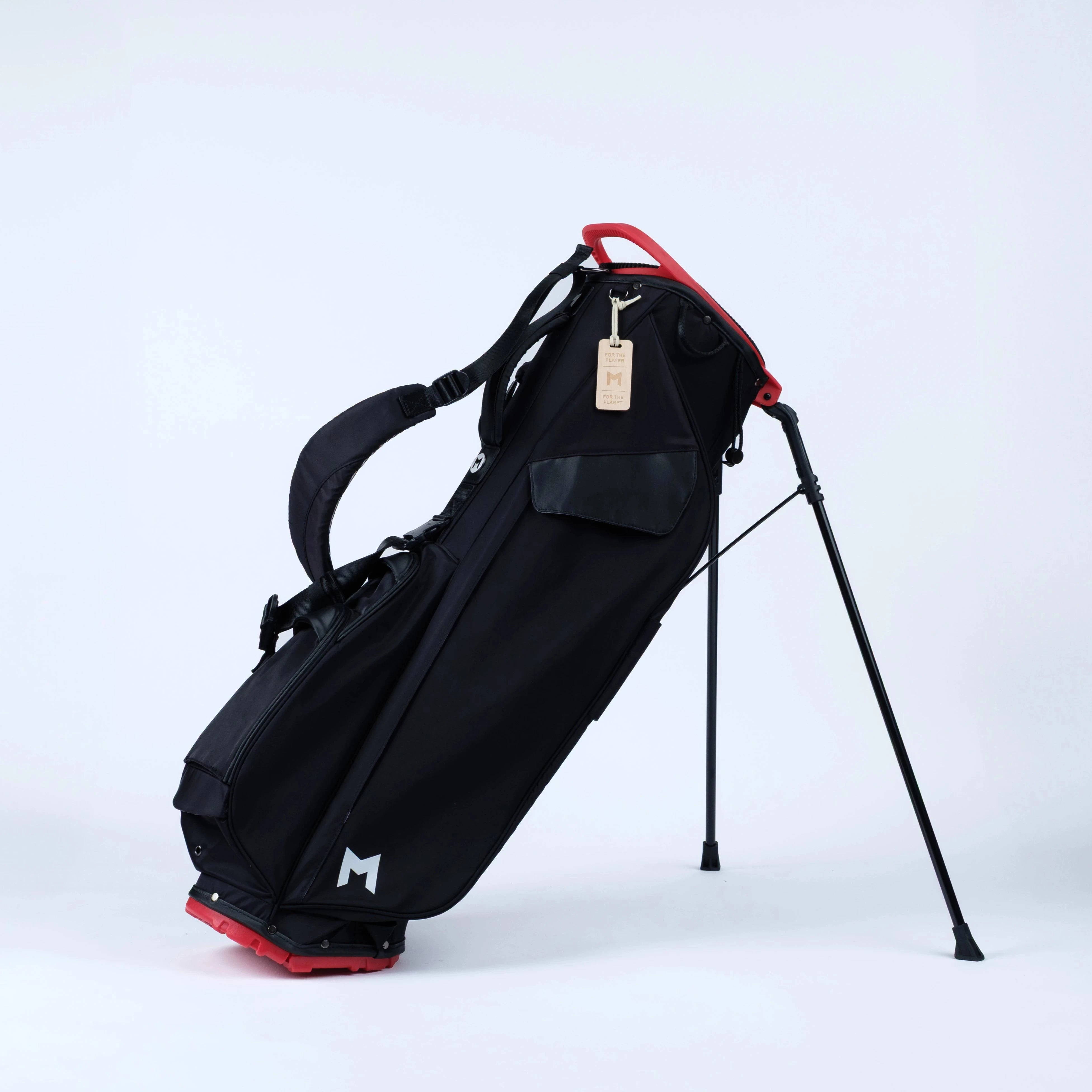 Black golf bag with red accents on stand with straps on a white background