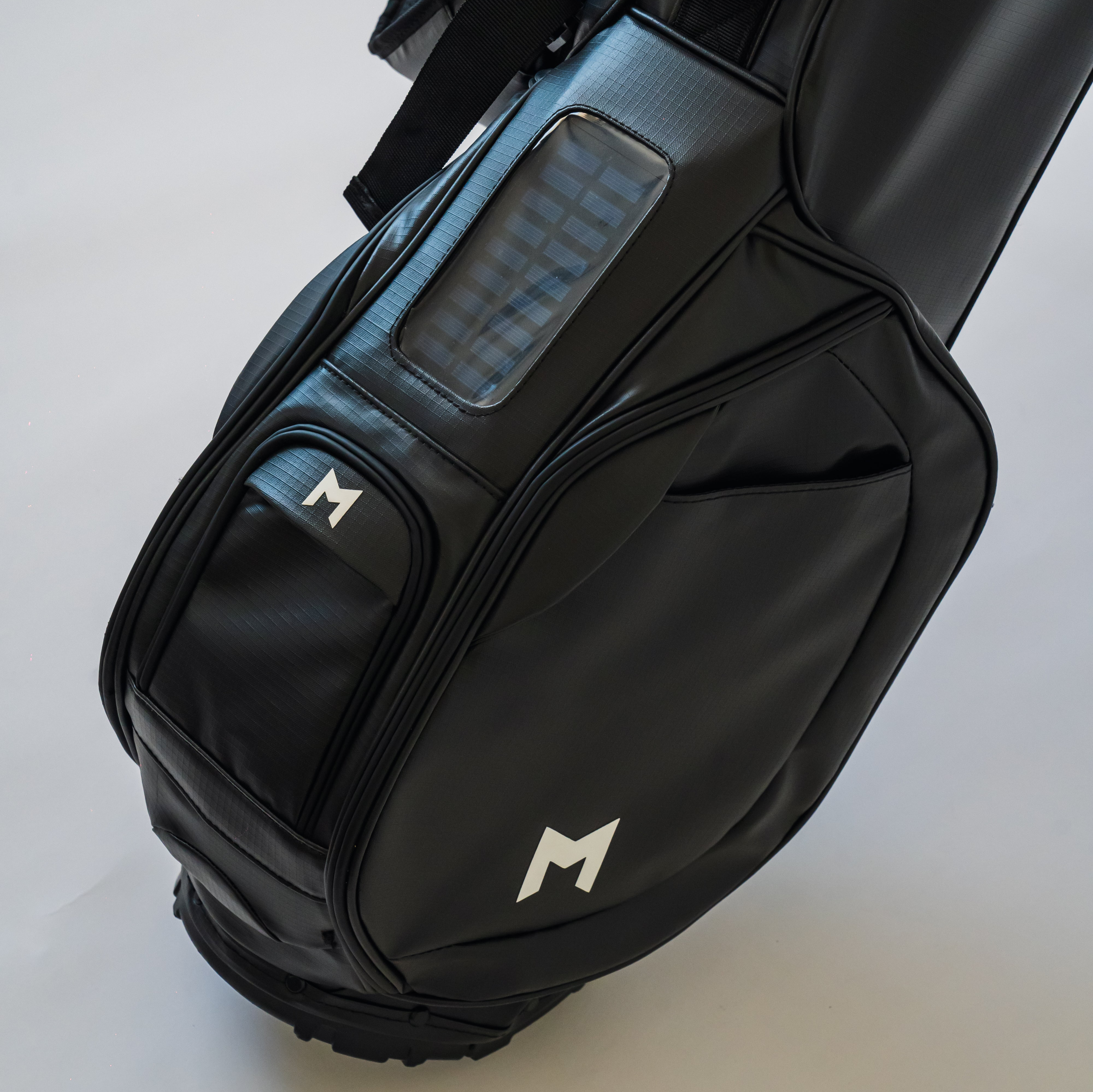 MNML GOLF's black MR1 personalized golf bag displaying the solar phone charger and magnetic-closure front ball pocket.