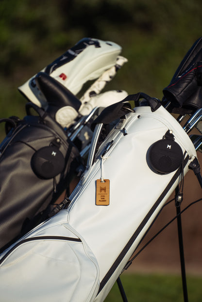 This is MNML GOLF's Waterproof bluetooth speaker on a white MR1 eco conscious golf bag.