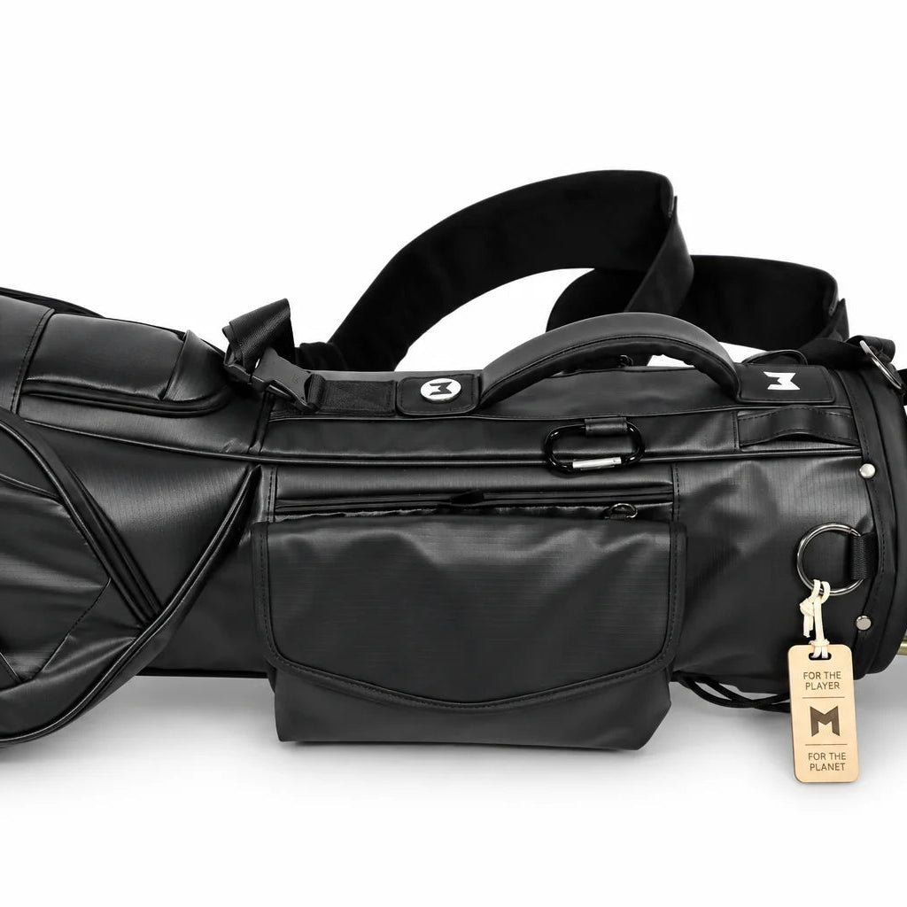 A black mini golf bag with multiple magnetic pockets, a shoulder strap, and a hanging wooden tag, shown against a plain white background.