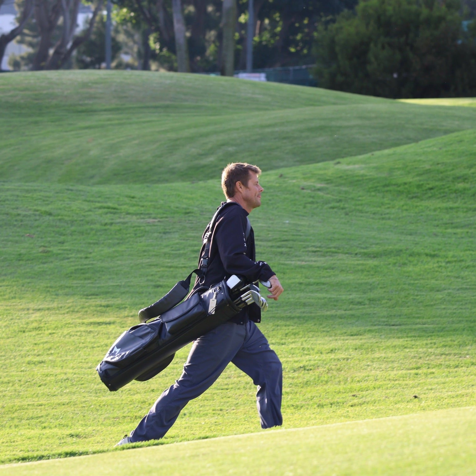 Golfer walking on a golf course carrying a golf bag