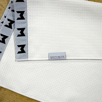 MNML GOLF white, sustainable waffle towel with grey and black logo detailing. 