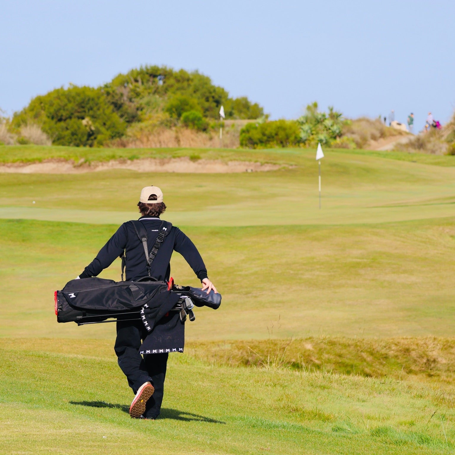 Person walking on a golf course carrying a golf bag
