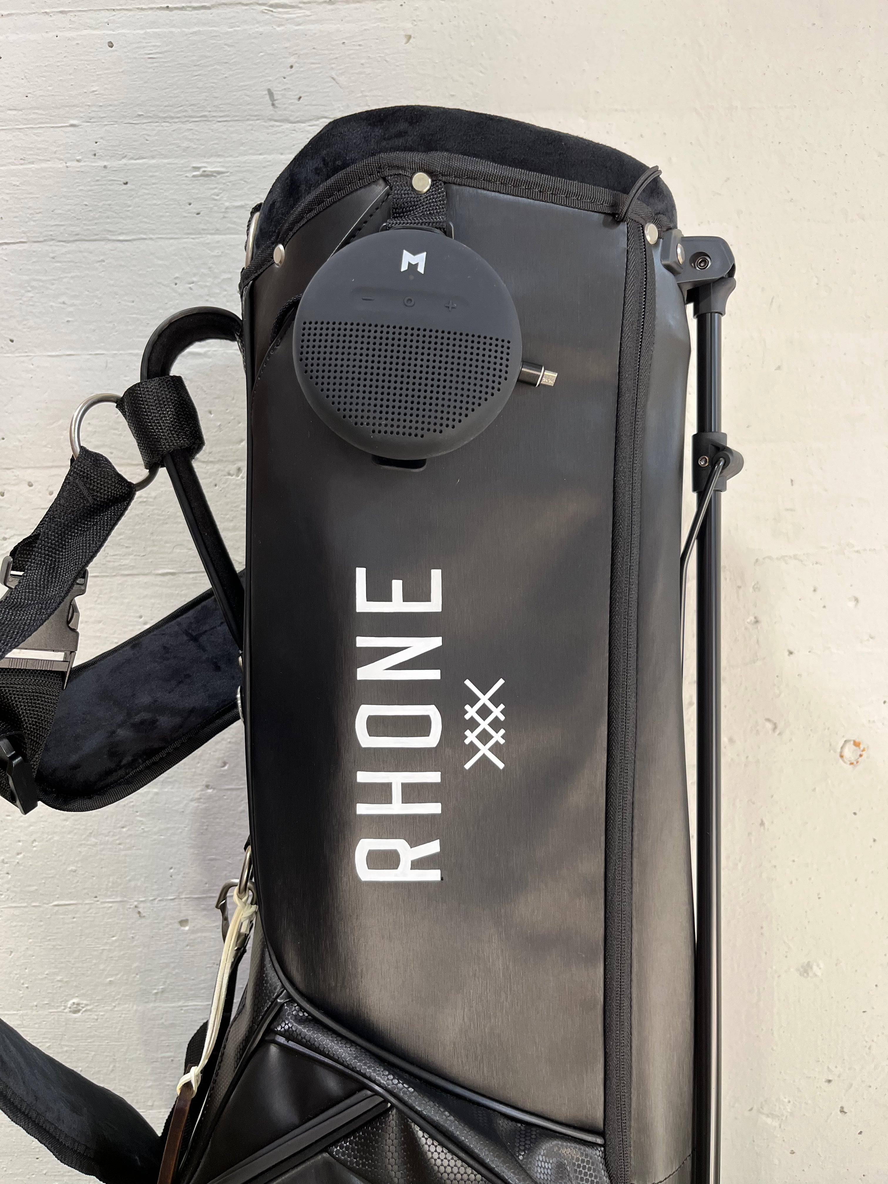 MNML GOLF and Rhone company logo painted in white, on a black golf bag.