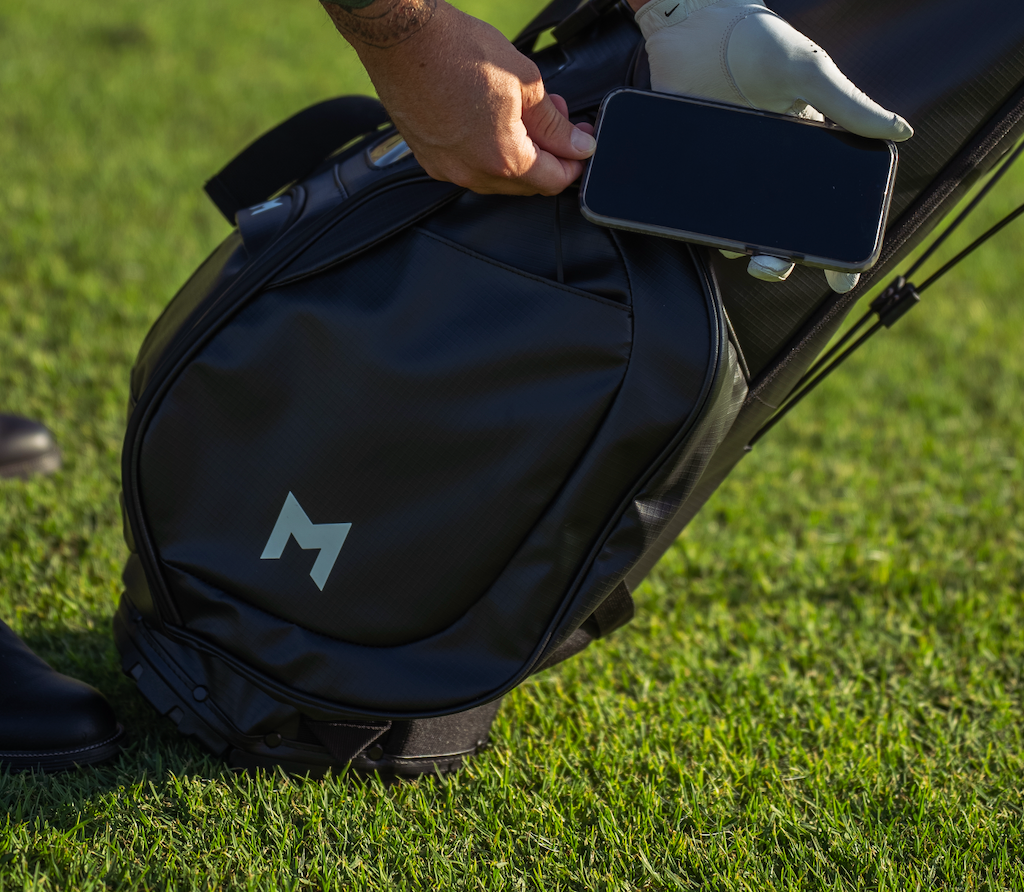 this is the mnml golf eco golf bag, in black, showing that you can plug your phone into our solar power bank, which comes with your mr1 purchase.