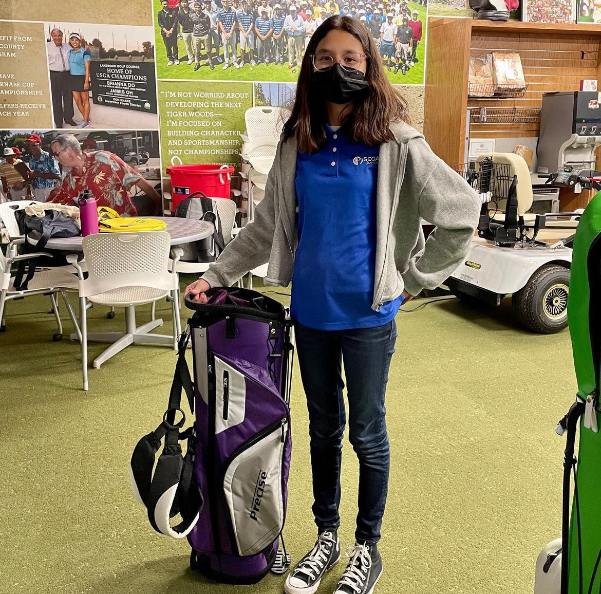 Junior golfer girl with a purple golf bag donated by MNML GOLF's trade it forward program.