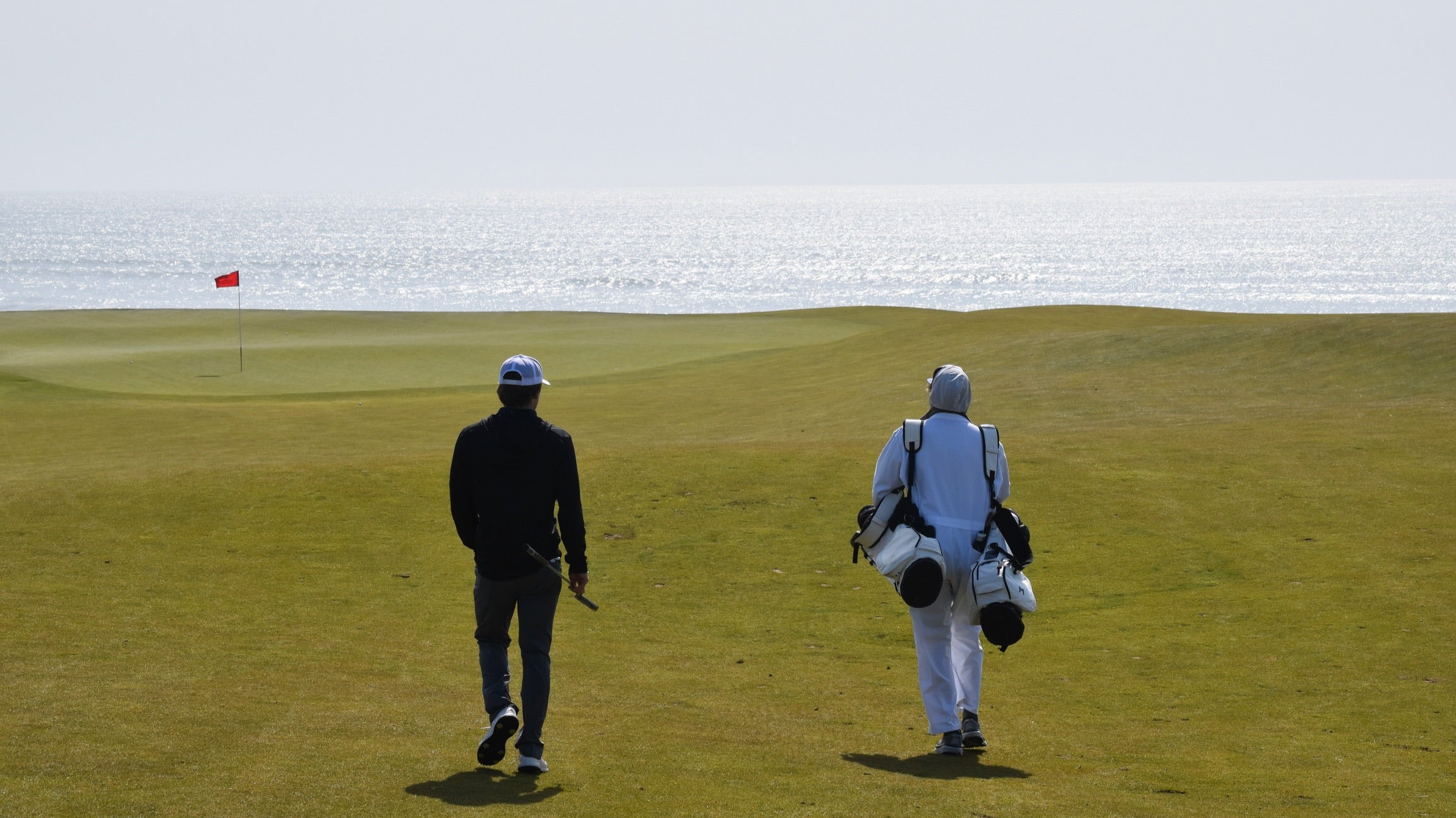 MNML GOLF team member, Campbell and caddy, walking down the fairway at Chamber's Bay golf course.