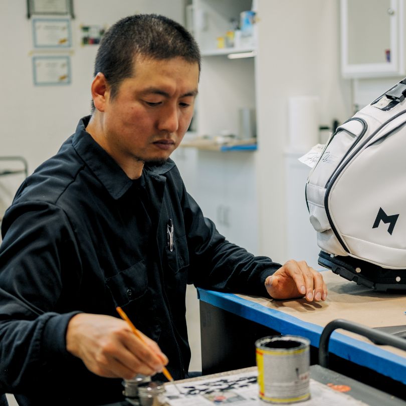 This is an image of our certified artist customizing a golf bag with hand painted artwork.
