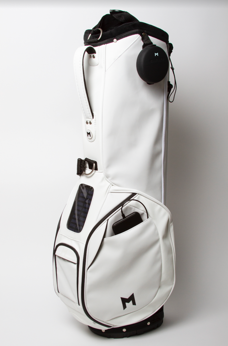 White Microsuede golf bag with MNML GOLF "M" logo on side. All magnetic pockets, range-finder and cell phone filming pocket, comes with a MNML GOLF ball marker. 4-way divider and thermal pocket (up to 5, 16oz bottles or 6 12oz cans). Free standing bag with internal stand mechanism and straps. Add on's include a solar panel cell phone charger, for Android or IPhone; waterproof bluetooth speaker with 8hr battery life available for purchase. 