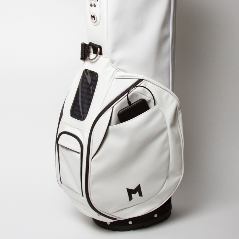 White Microsuede golf bag with MNML GOLF "M" logo on side. All magnetic pockets, range-finder and cell phone filming pocket, comes with a MNML GOLF ball marker. 4-way divider and thermal pocket (up to 5, 16oz bottles or 6 12oz cans). Free standing bag with internal stand mechanism and straps. Add on's include a solar panel cell phone charger, for Android or IPhone; waterproof bluetooth speaker with 8hr battery life available for purchase. 