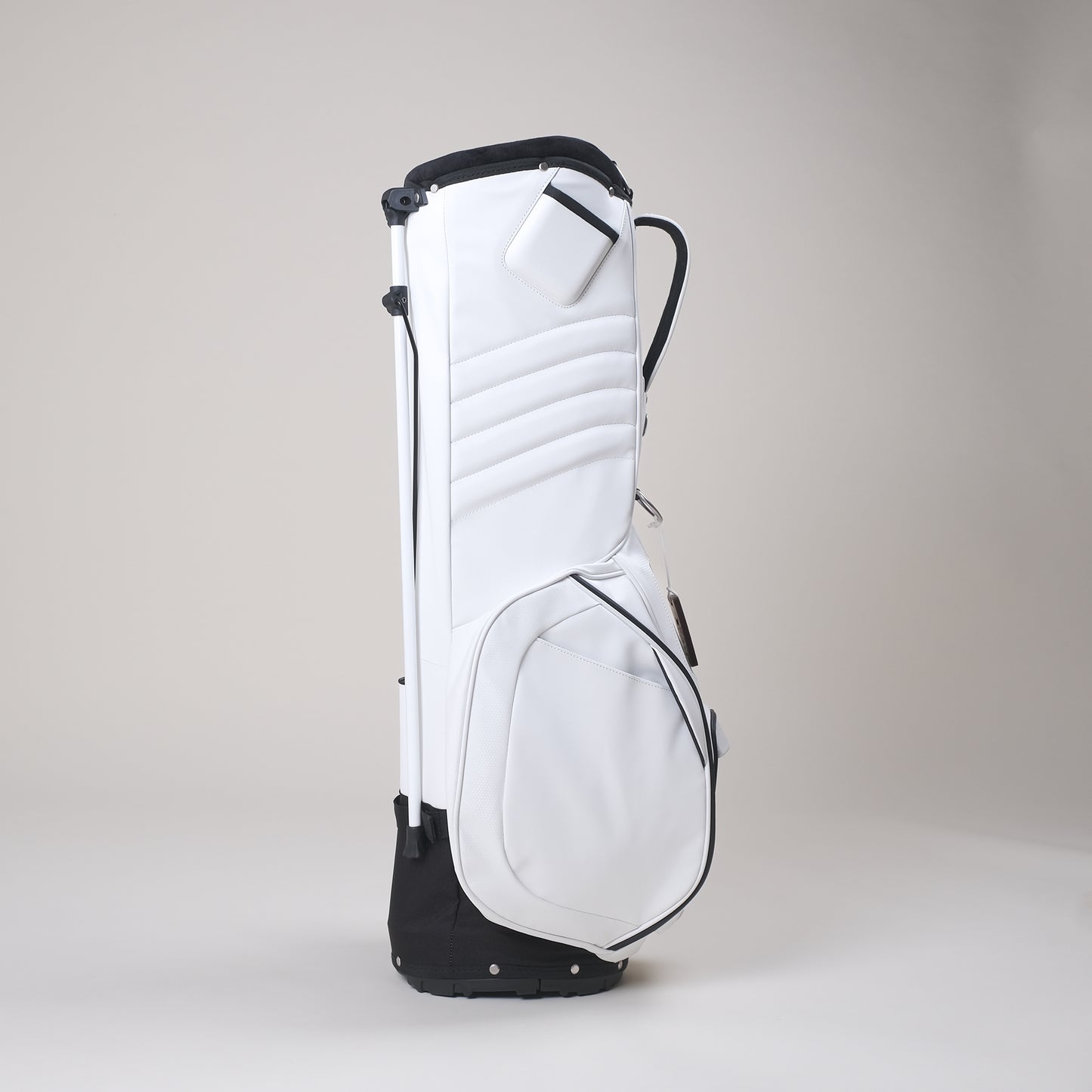 Side view of white MNML GOLF bag displaying phone pocket for filming, extra storage magnetic pockets, standing golf bag and handle. 